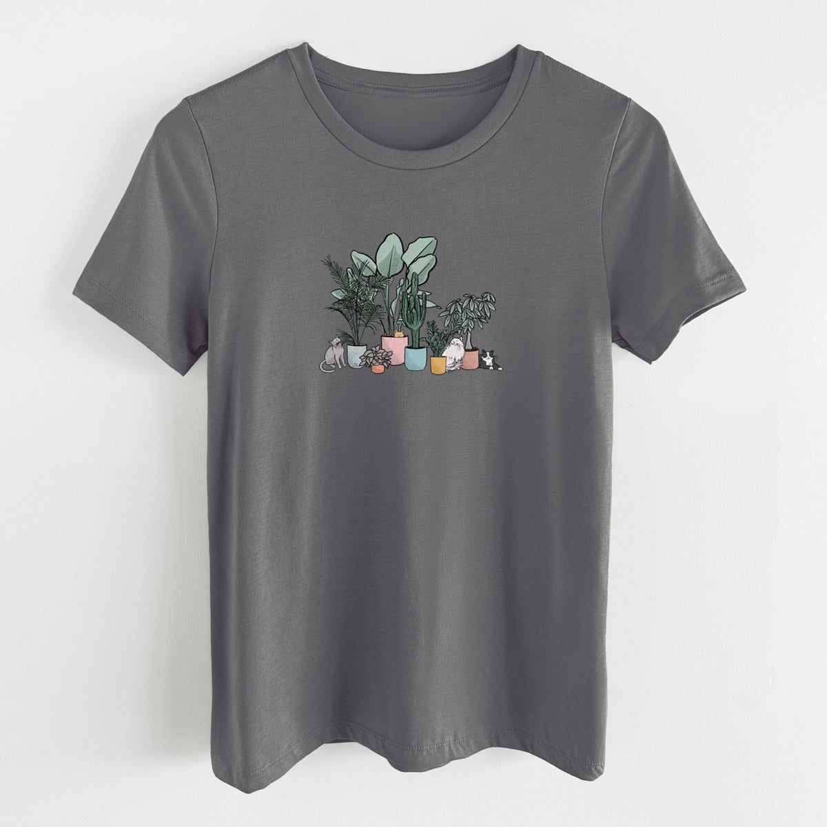 Asphalt women's relaxed fit cotton t-shirt laid flat, printed with a full-color illustration of cats lounging among potted houseplants.
