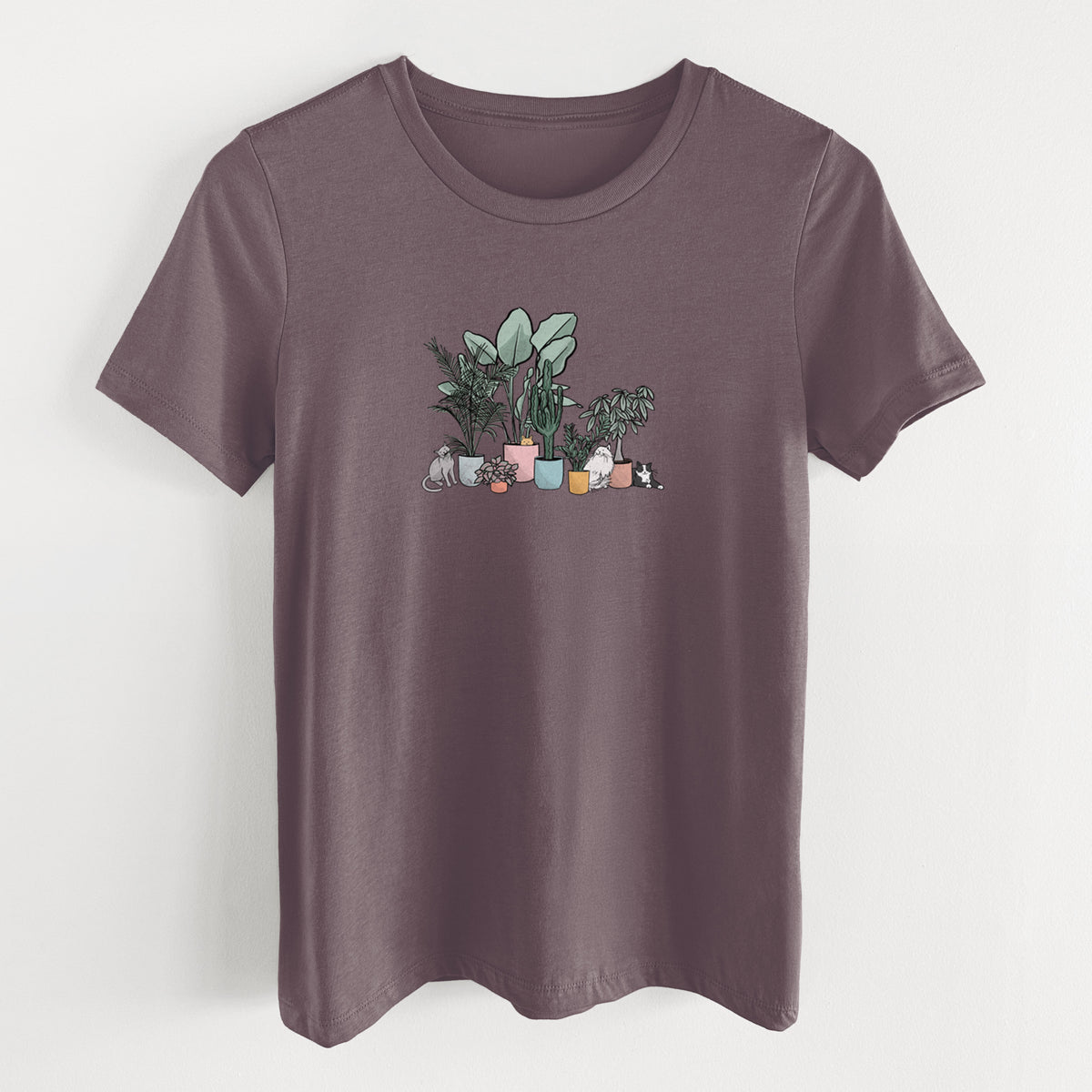 Purple storm women's relaxed fit cotton t-shirt laid flat, printed with a full-color illustration of cats lounging among potted houseplants.
