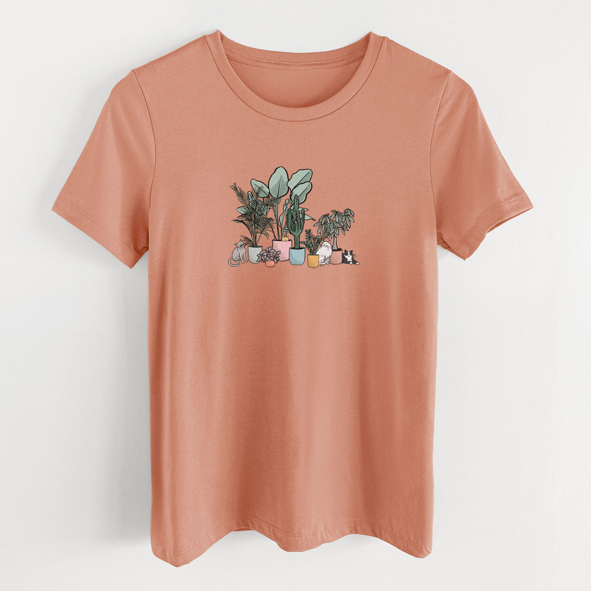Terracotta orange women's relaxed fit cotton t-shirt laid flat, printed with a full-color illustration of cats lounging among potted houseplants.