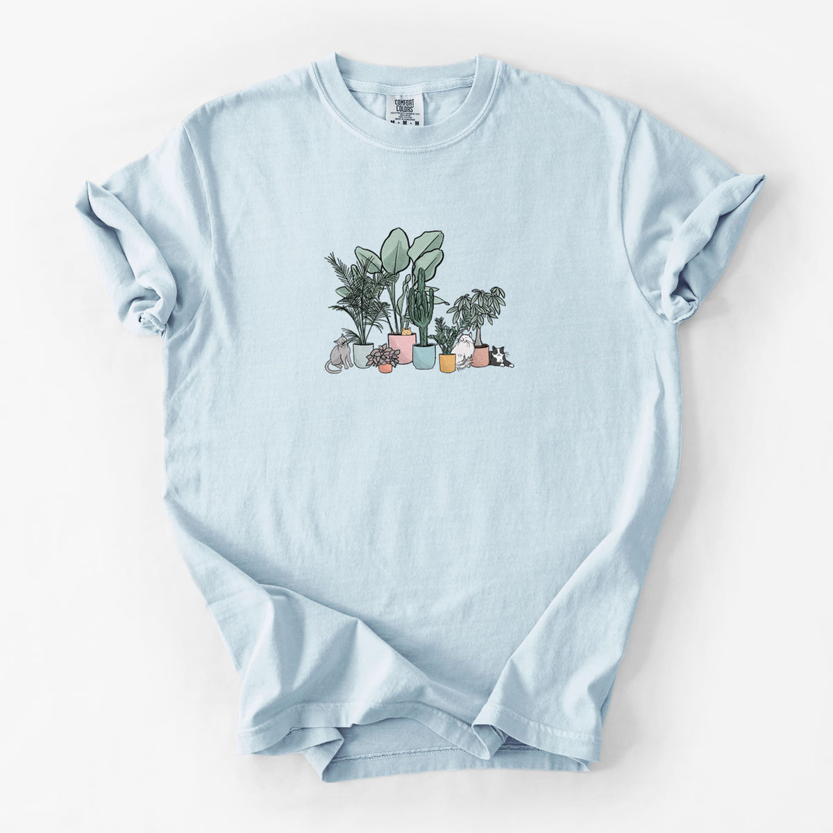 Chambray blue Comfort Colors t-shirt laid flat, printed with a full-color illustration of cats lounging among potted houseplants.