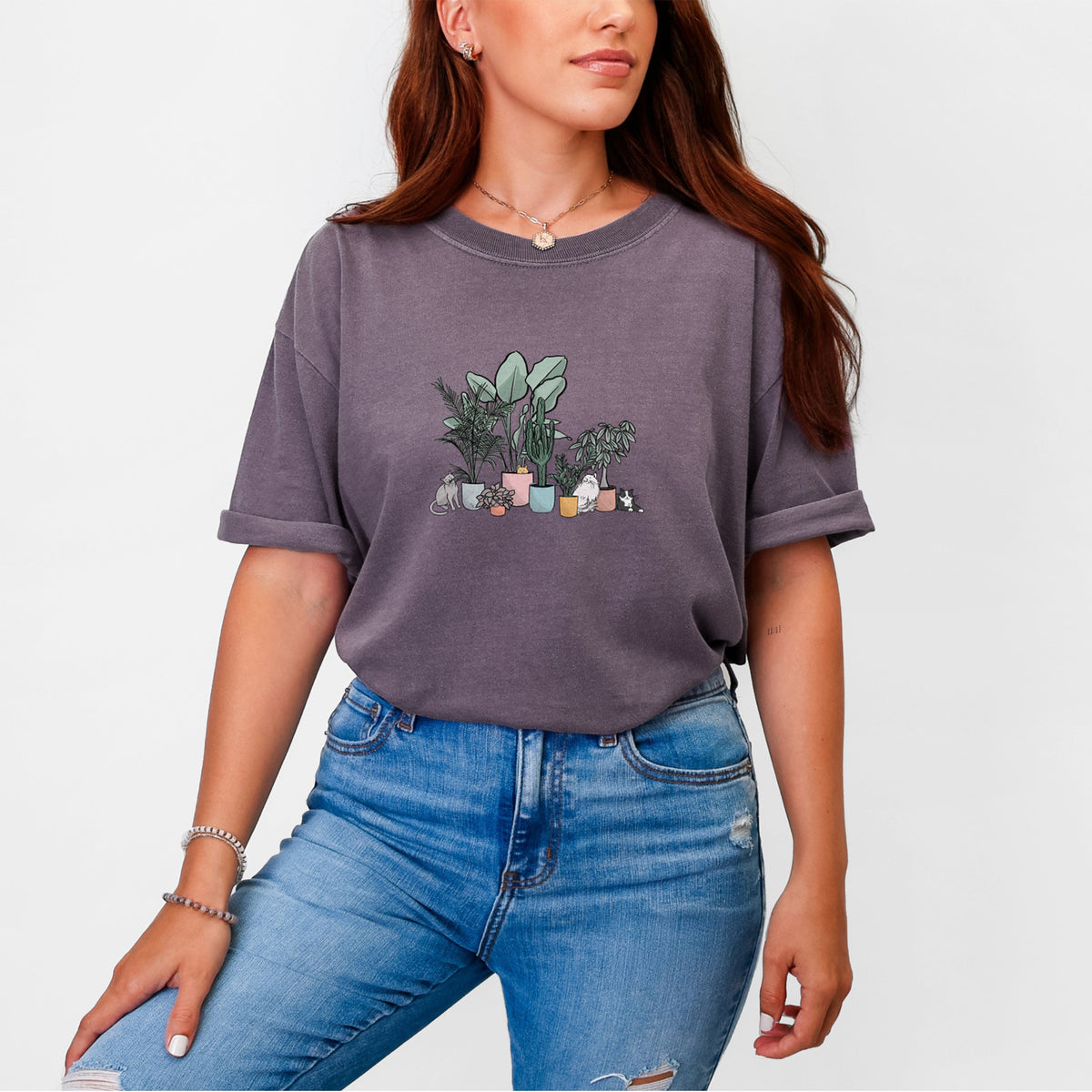 Woman wearing a Comfort Colors t-shirt printed with a full-color illustration of cats lounging among potted houseplants.