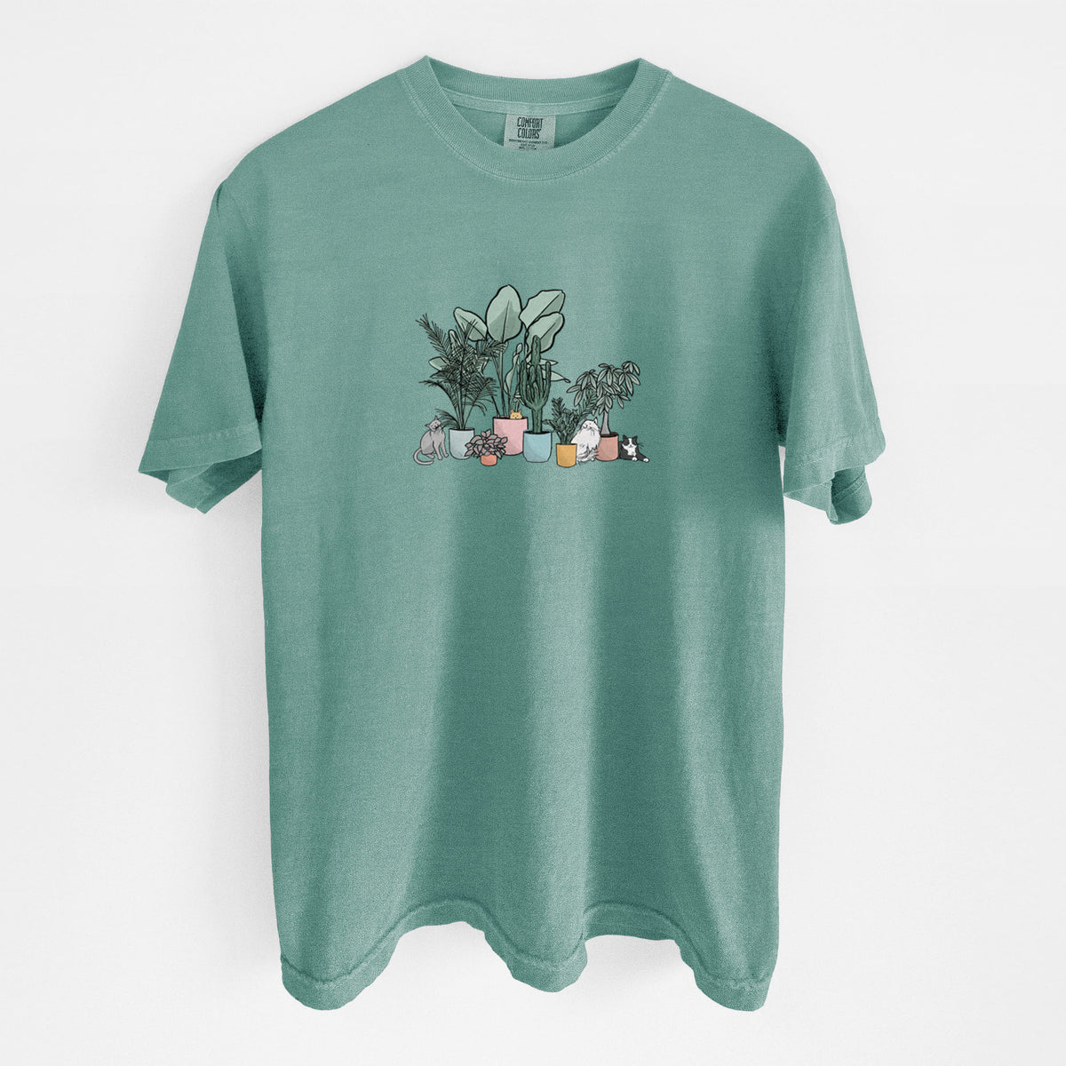 Reef green Comfort Colors t-shirt laid flat, printed with a full-color illustration of cats lounging among potted houseplants.