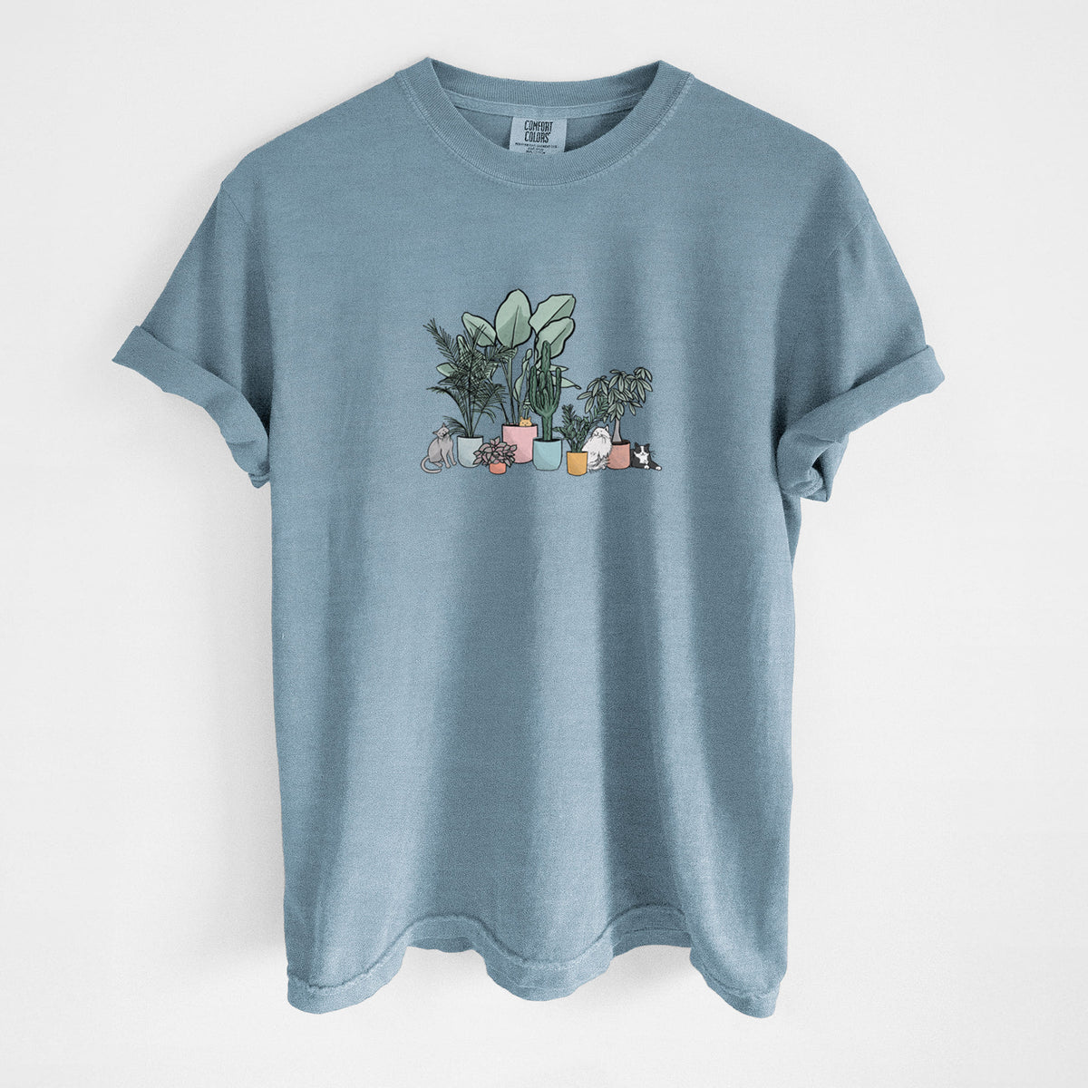 Steel blue Comfort Colors t-shirt laid flat, printed with a full-color illustration of cats lounging among potted houseplants.