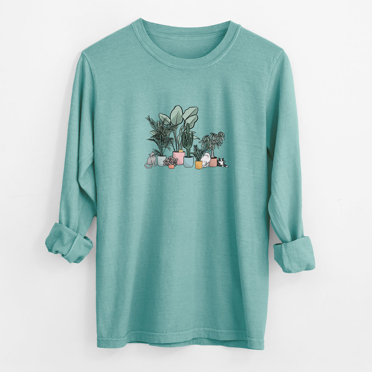 Reef green Comfort Colors long sleeve shirt laid flat with the cuffs rolled, printed with a full-color illustration of cats lounging among potted houseplants.