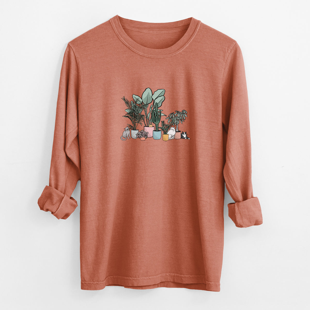 Yam burnt orange Comfort Colors long sleeve shirt laid flat with the cuffs rolled, printed with a full-color illustration of cats lounging among potted houseplants.