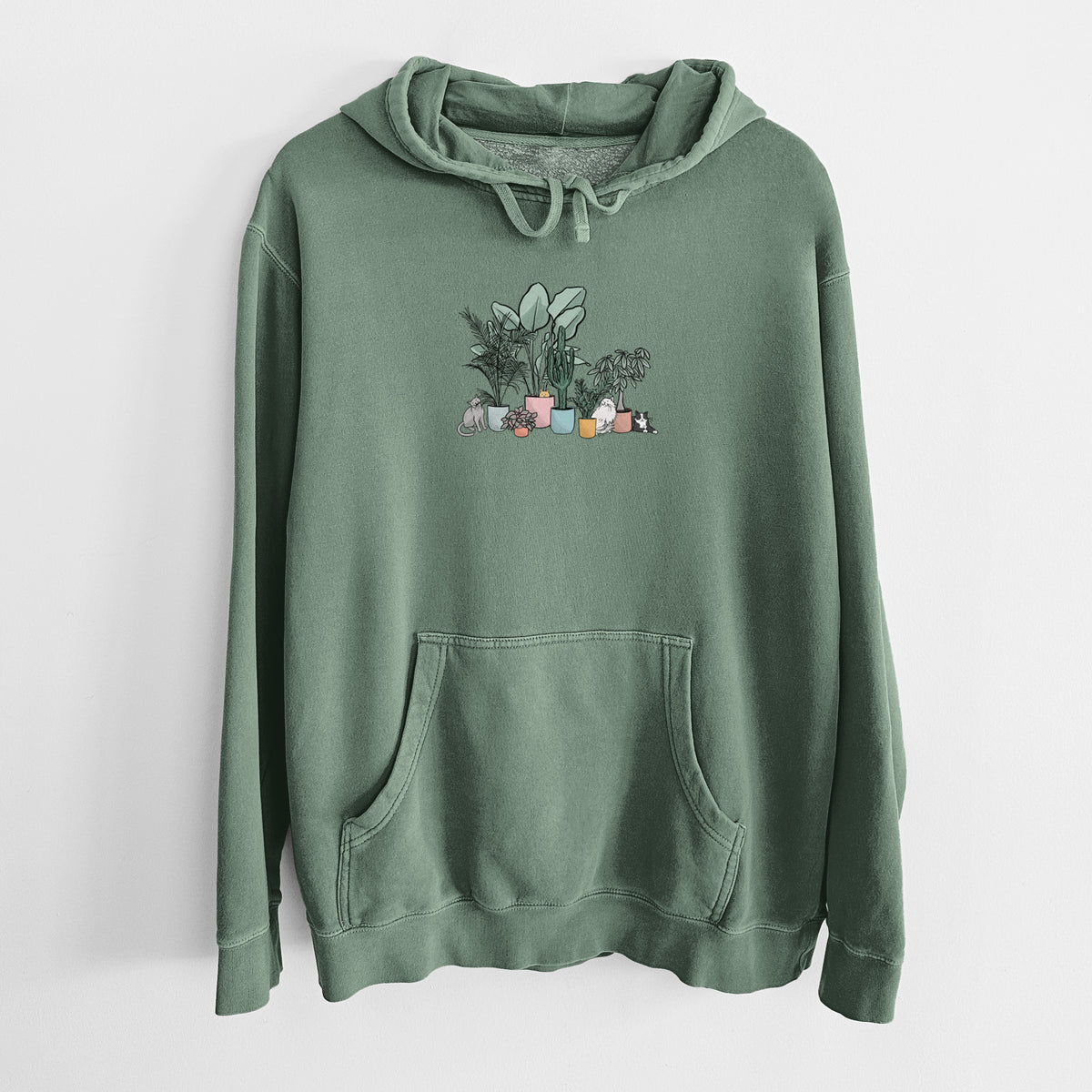 Alpine green pigment dyed hoodie laid flat, printed with a full-color illustration of cats lounging among potted houseplants.