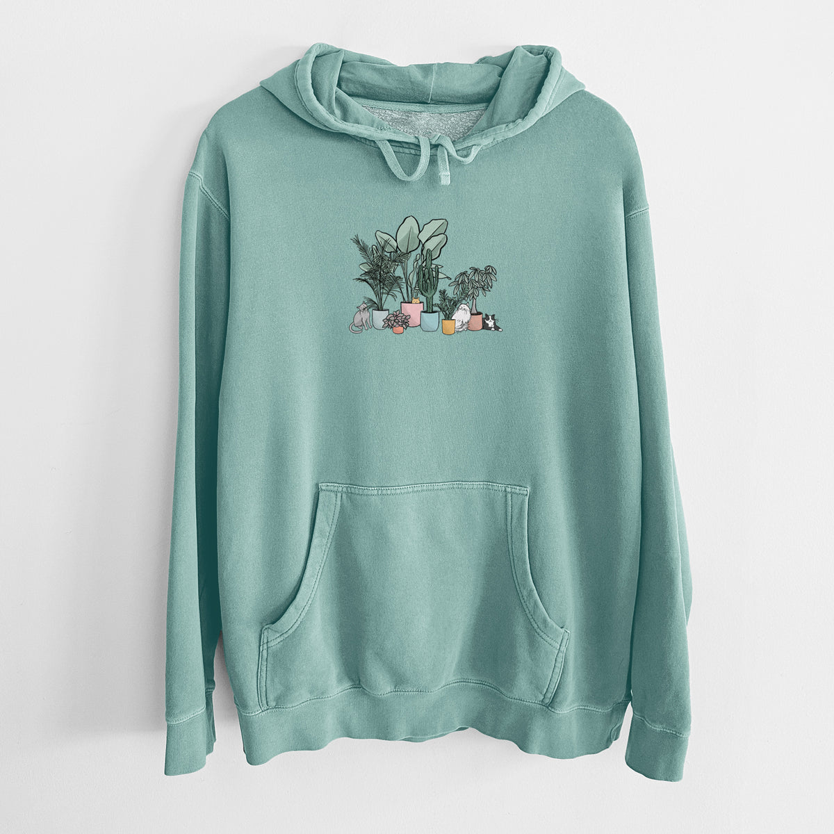 Mint green pigment dyed hoodie laid flat, printed with a full-color illustration of cats lounging among potted houseplants.