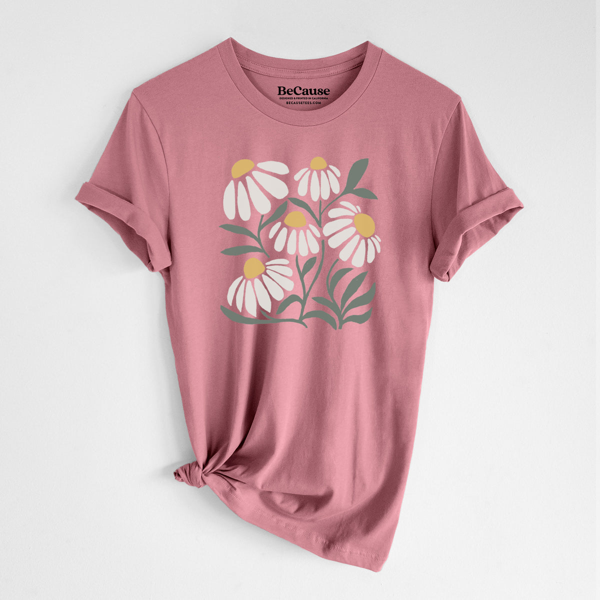 Mauve pink lightweight cotton t-shirt laid flat with the sleeves rolled, printed with a soft full-color illustration of white chamomile flowers and green leaves.