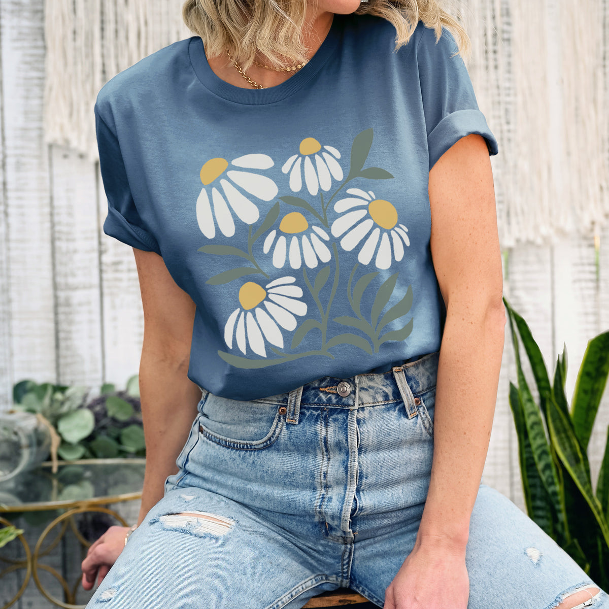 Woman wearing a steel blue lightweight cotton t-shirt printed with a soft full-color illustration of white chamomile flowers and green leaves.