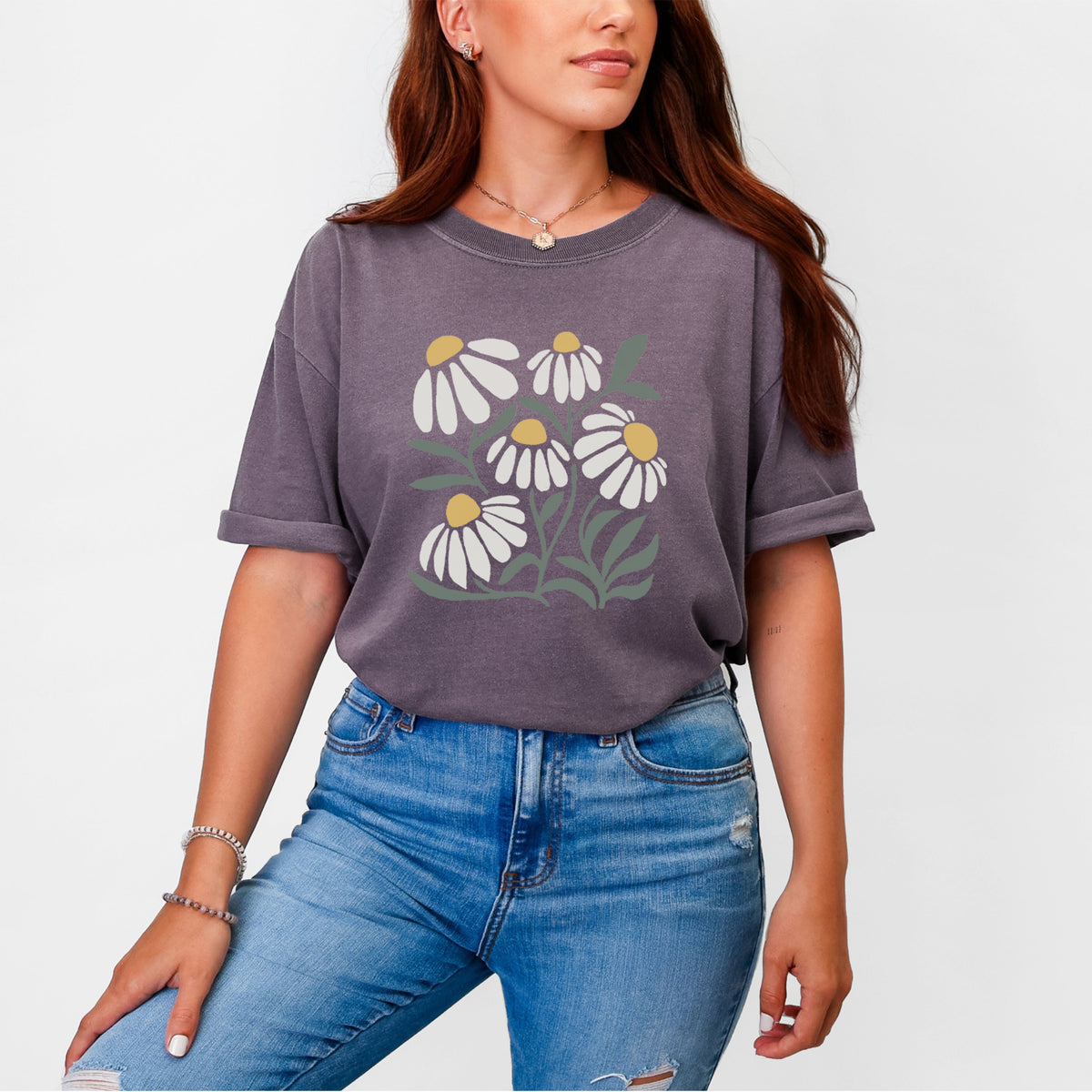 Woman wearing a Comfort Colors t-shirt printed with a soft full-color illustration of white chamomile flowers and green leaves.