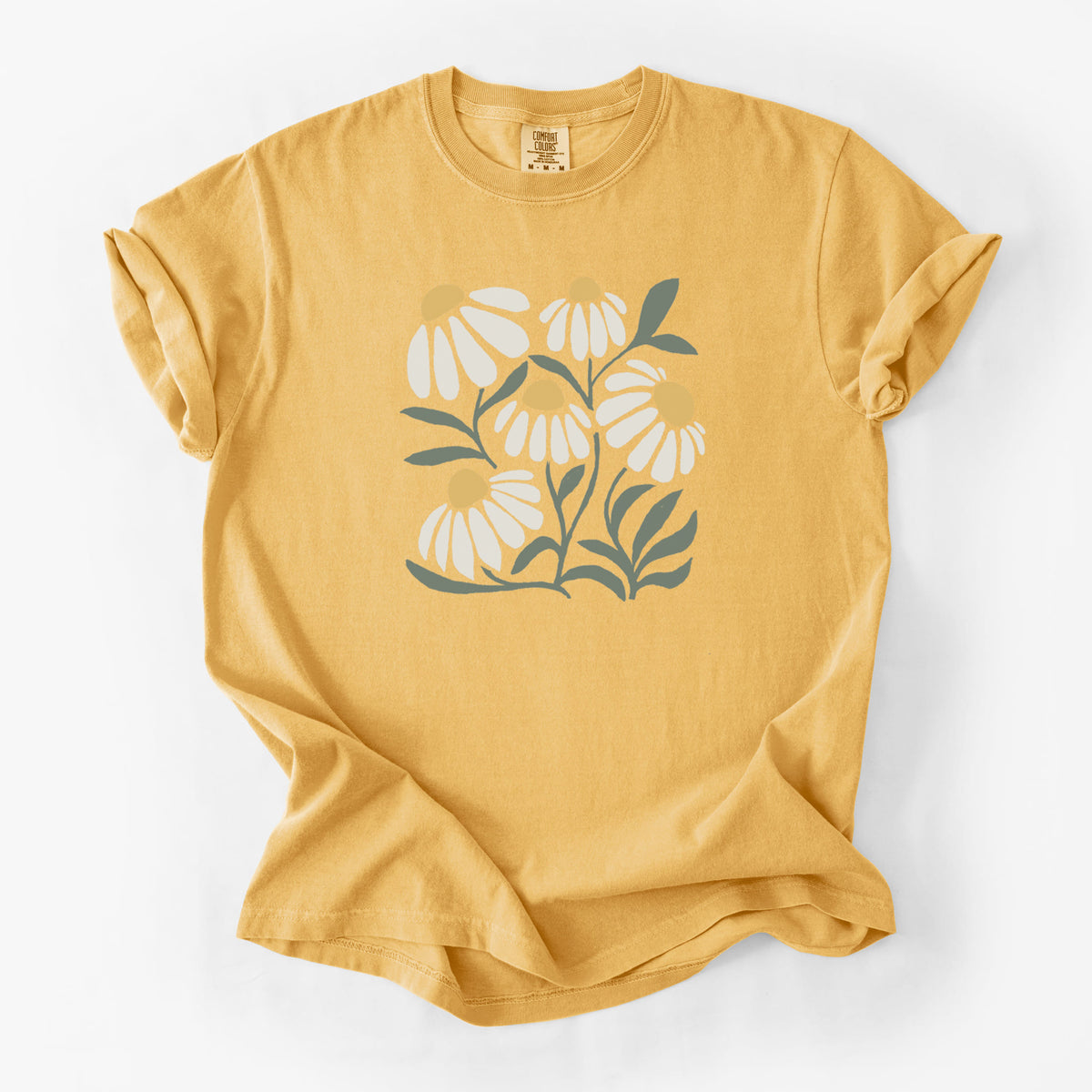 Golden wheat yellow Comfort Colors t-shirt laid flat, printed with a soft full-color illustration of white chamomile flowers and green leaves.