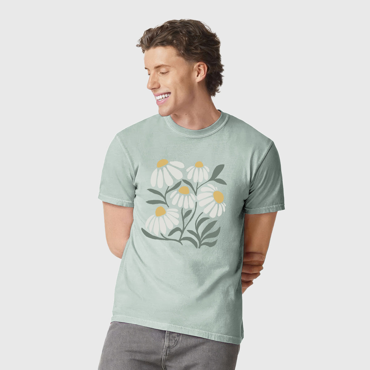Man wearing a Comfort Colors t-shirt printed with a soft full-color illustration of white chamomile flowers and green leaves.
