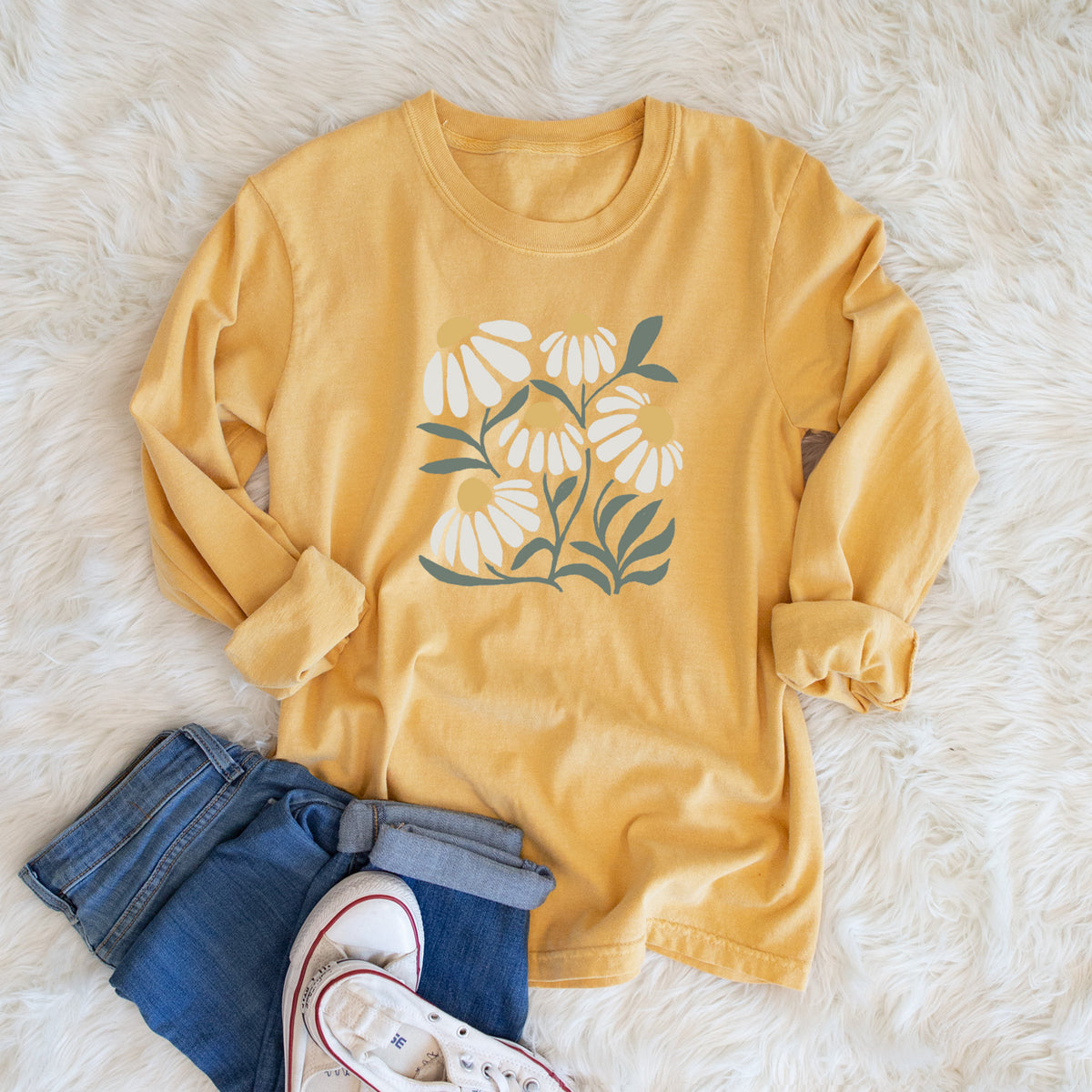 Golden wheat yellow Comfort Colors long sleeve shirt printed with a soft full-color illustration of white chamomile flowers and green leaves, shown in a lifestyle photo.
