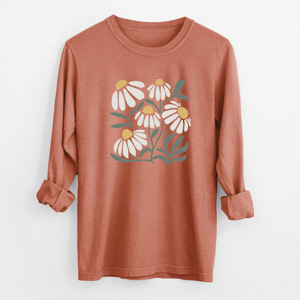 Yam burnt orange Comfort Colors long sleeve shirt laid flat with the cuffs rolled, printed with a soft full-color illustration of white chamomile flowers and green leaves.