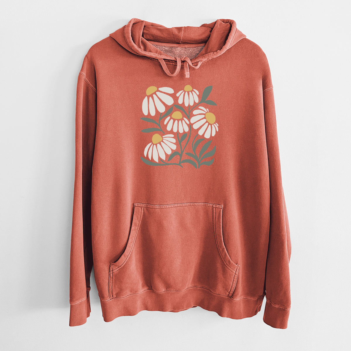 Amber orange pigment dyed hoodie laid flat, printed with a soft full-color illustration of white chamomile flowers and green leaves.