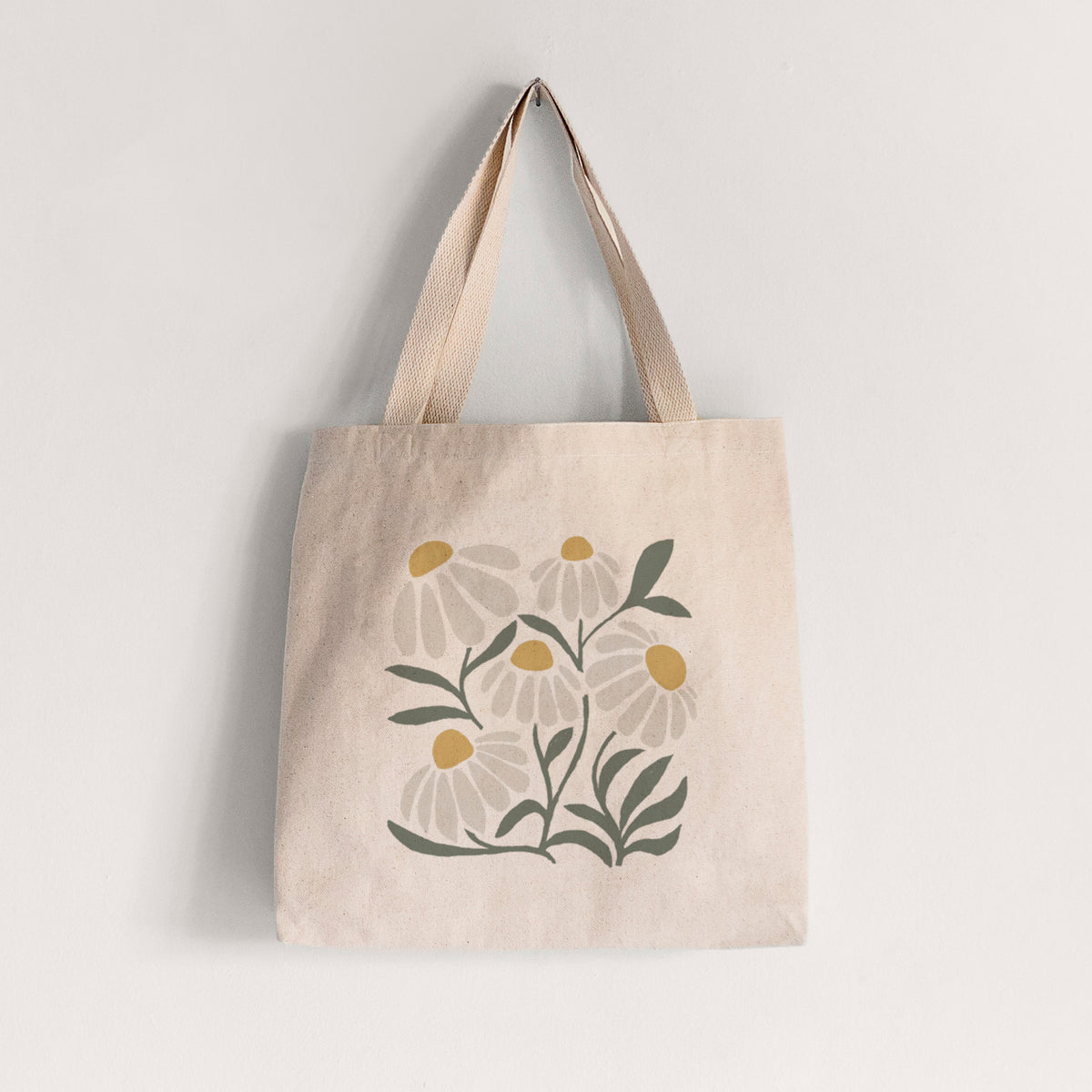 Natural canvas tote bag printed with a soft full-color illustration of white chamomile flowers and green leaves.