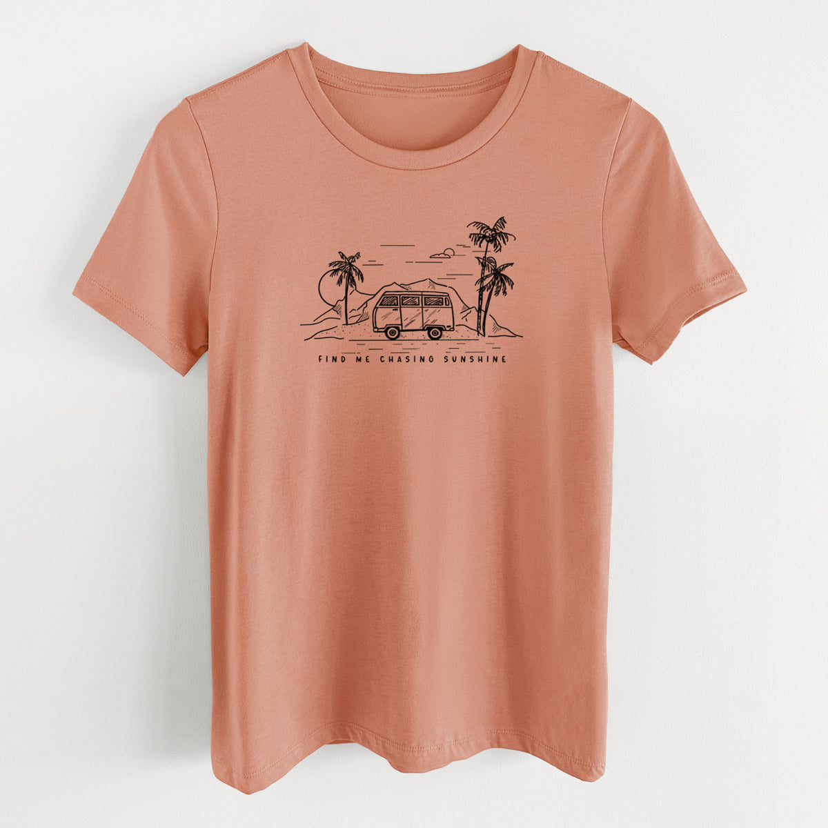 Terracotta orange women's relaxed fit cotton t-shirt laid flat, printed with a black ink illustration of a camper van under palm trees and the sun, with the words Find Me Chasing Sunshine.