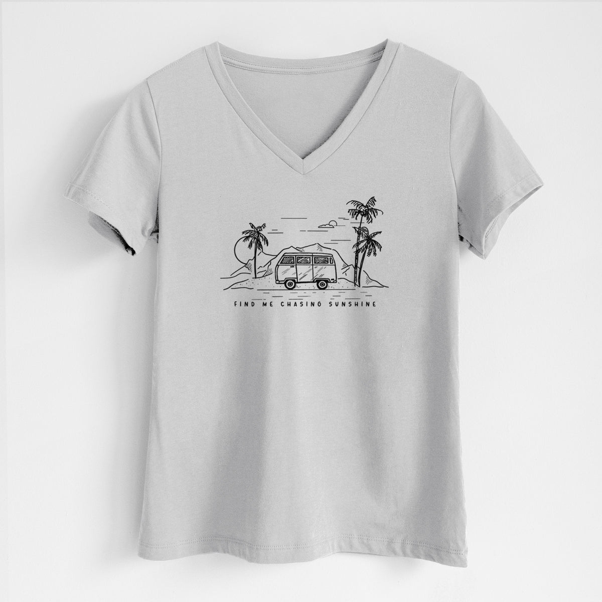 Lunar grey women's relaxed fit cotton V-neck t-shirt laid flat, printed with a black ink illustration of a camper van under palm trees and the sun, with the words Find Me Chasing Sunshine.