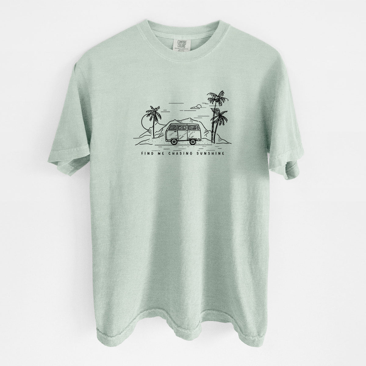 Bay green Comfort Colors t-shirt laid flat, printed with a black ink illustration of a camper van under palm trees and the sun, with the words Find Me Chasing Sunshine.