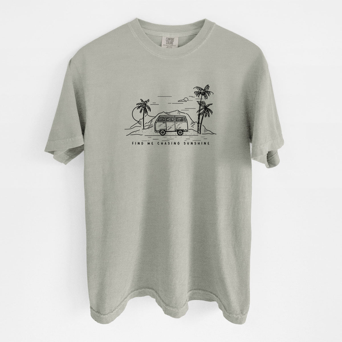 Sandstone beige Comfort Colors t-shirt laid flat, printed with a black ink illustration of a camper van under palm trees and the sun, with the words Find Me Chasing Sunshine.