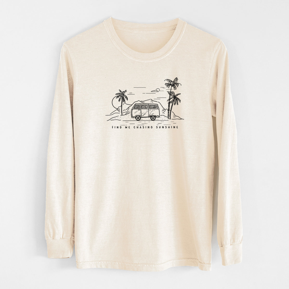 Ivory Comfort Colors long sleeve shirt laid flat, printed with a black ink illustration of a camper van under palm trees and the sun, with the words Find Me Chasing Sunshine.
