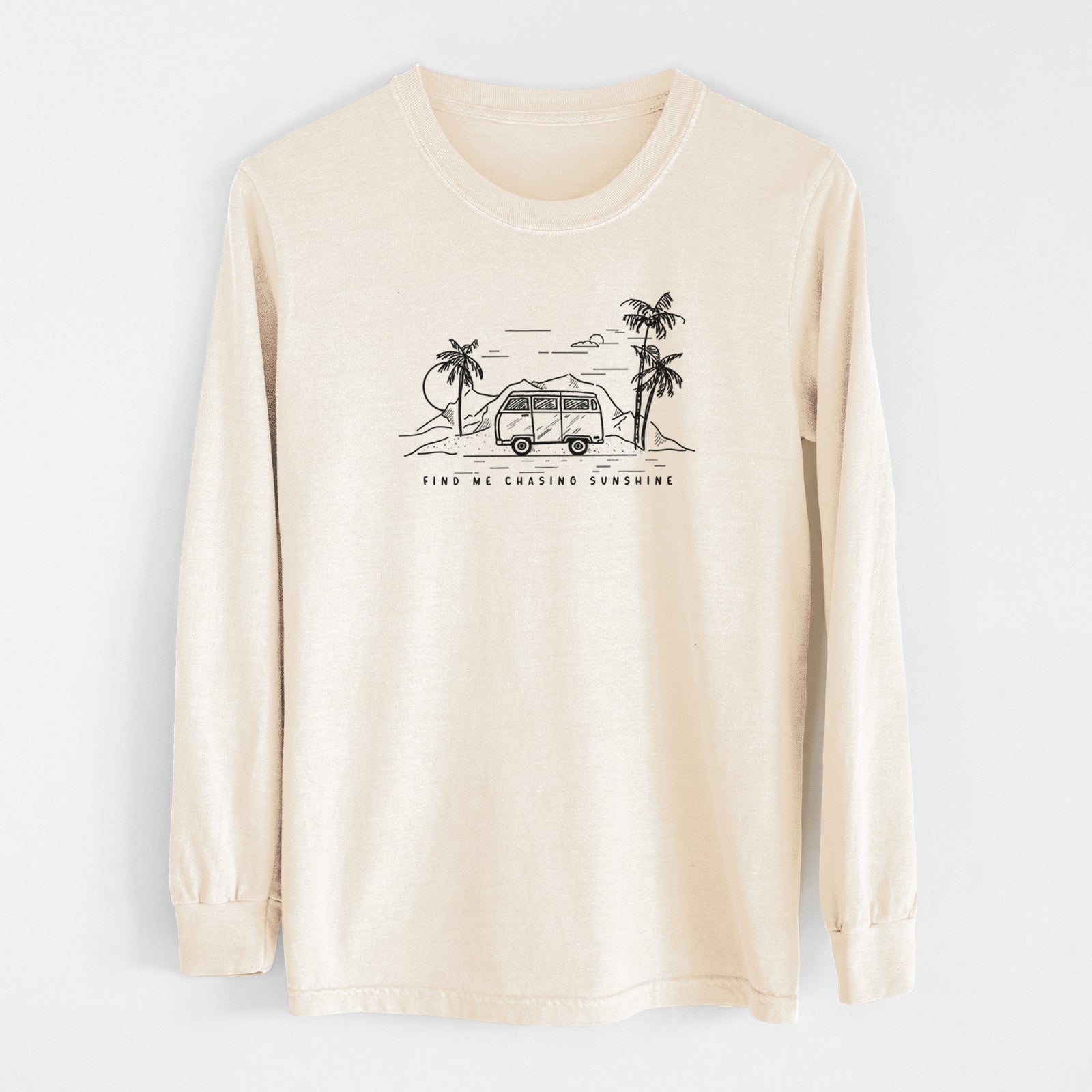 Ivory Comfort Colors long sleeve shirt laid flat, printed with a black ink illustration of a camper van under palm trees and the sun, with the words Find Me Chasing Sunshine.