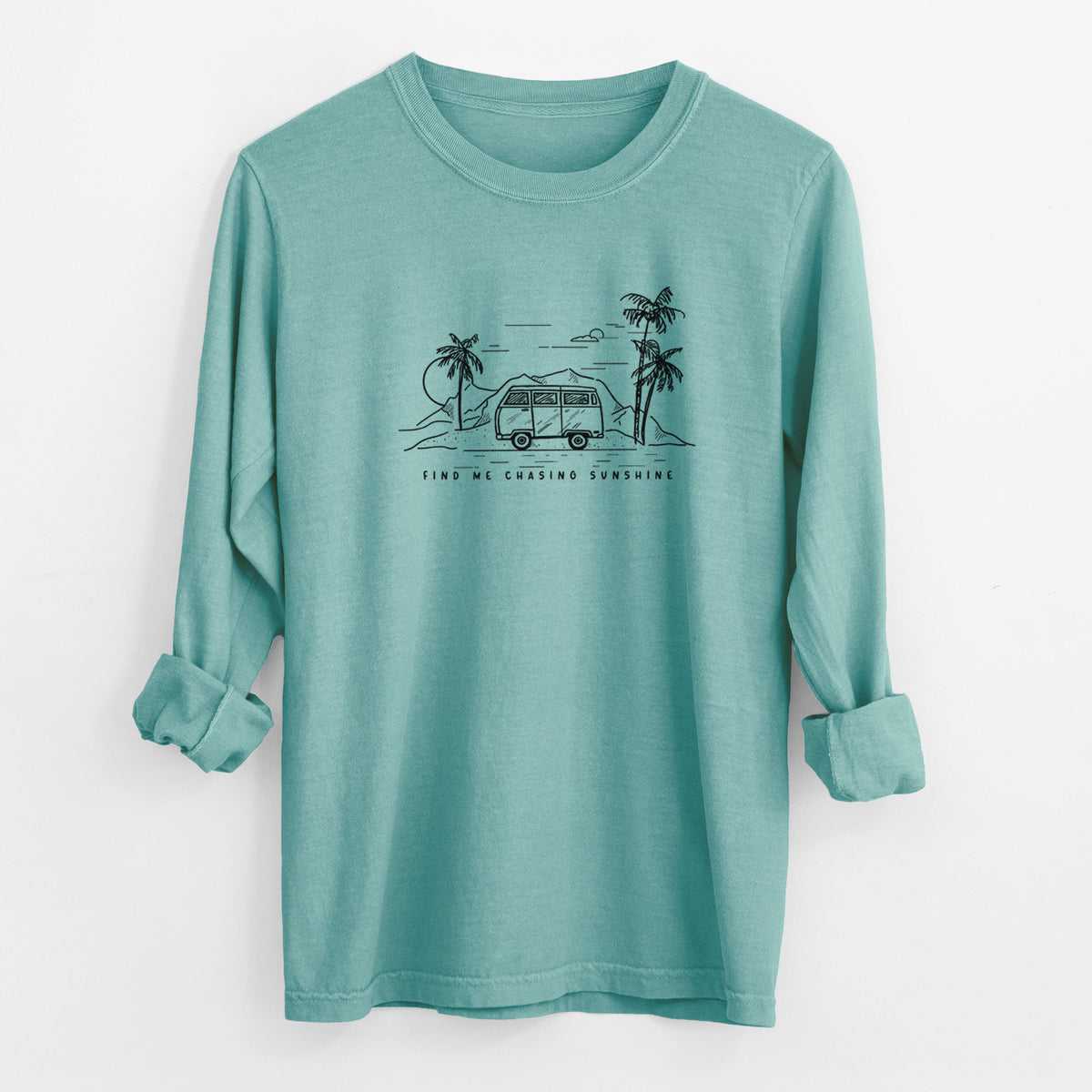 Reef green Comfort Colors long sleeve shirt laid flat with the cuffs rolled, printed with a black ink illustration of a camper van under palm trees and the sun, with the words Find Me Chasing Sunshine.