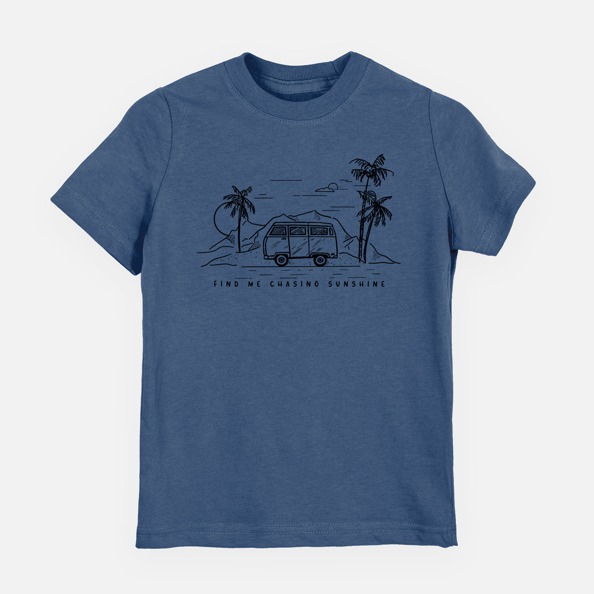 Indigo blue youth t-shirt laid flat, printed with a black ink illustration of a camper van under palm trees and the sun, with the words Find Me Chasing Sunshine.