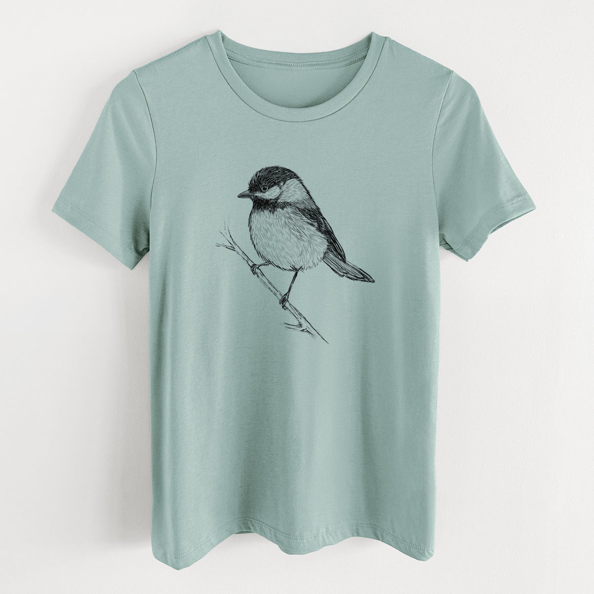 Dusty blue women's relaxed fit cotton t-shirt laid flat, printed with a detailed black ink sketch of a black-capped chickadee perched on a branch.