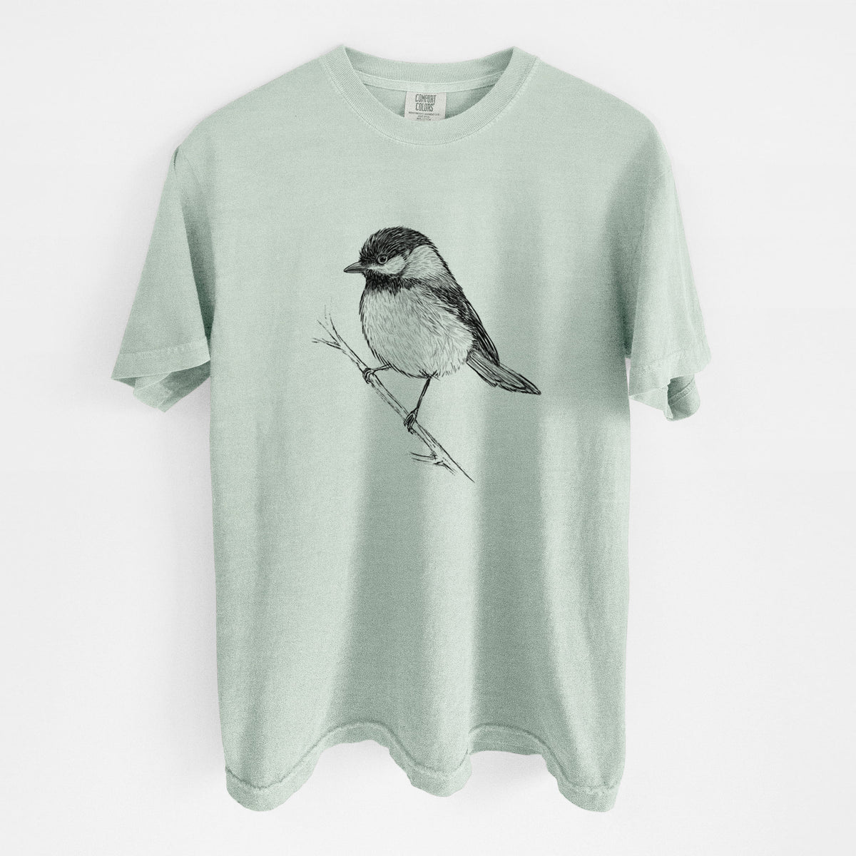 Bay green Comfort Colors t-shirt laid flat, printed with a detailed black ink sketch of a black-capped chickadee perched on a branch.