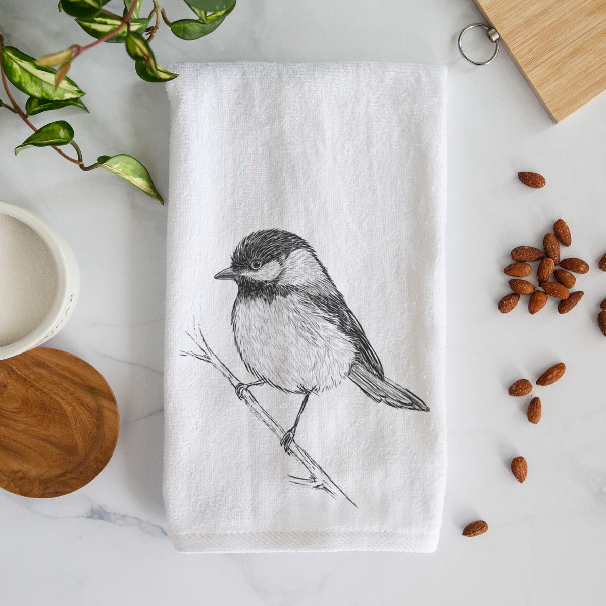 White hand towel printed with a detailed black ink sketch of a black-capped chickadee perched on a branch.
