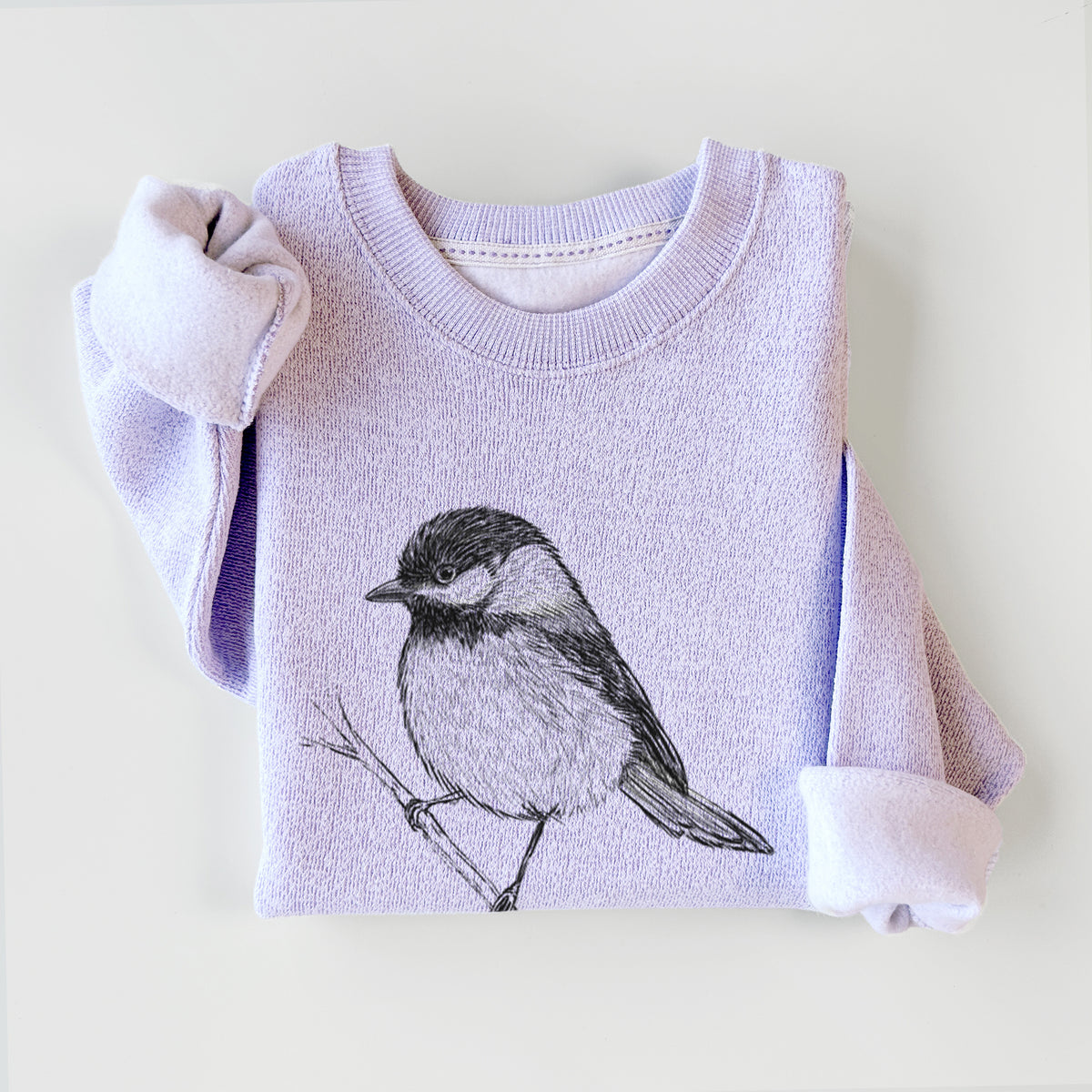 Ice purple knit sweatshirt printed with a detailed black ink sketch of a black-capped chickadee perched on a branch, styled flat.