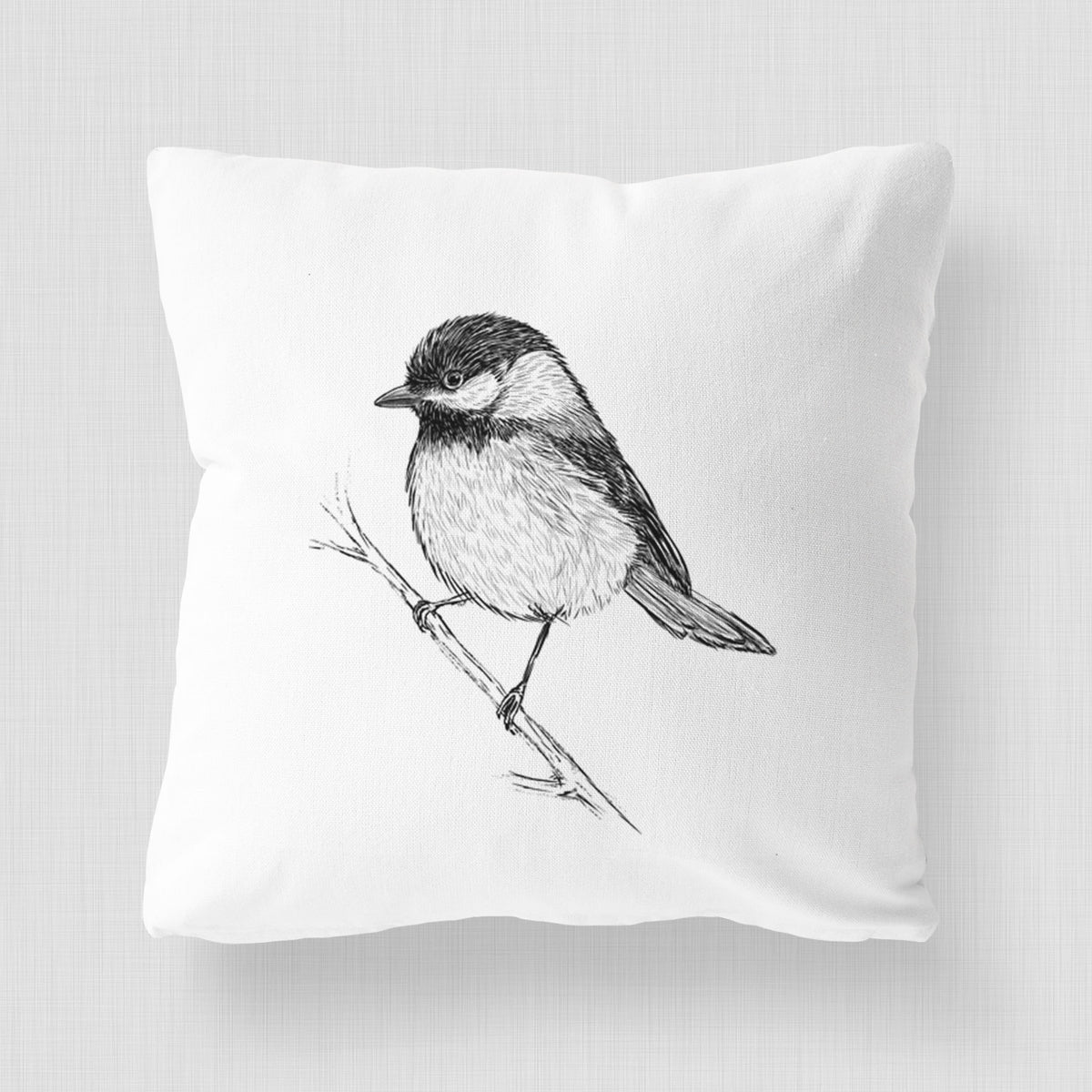 White pillow cover printed with a detailed black ink sketch of a black-capped chickadee perched on a branch.