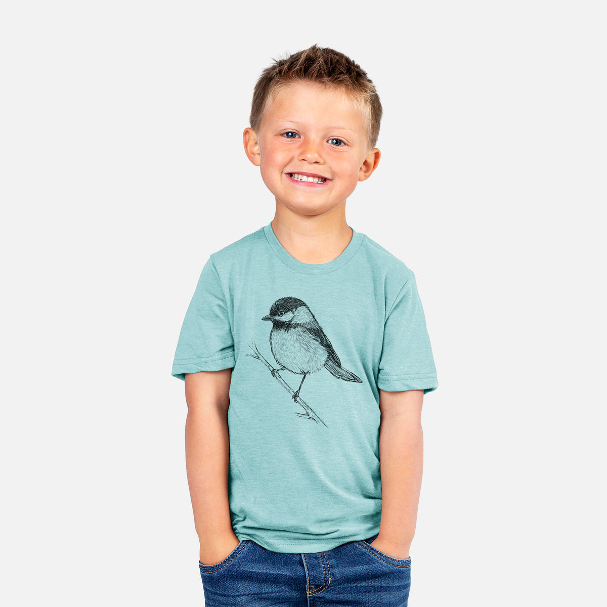 Smiling boy wearing a youth t-shirt printed with a detailed black ink sketch of a black-capped chickadee perched on a branch.