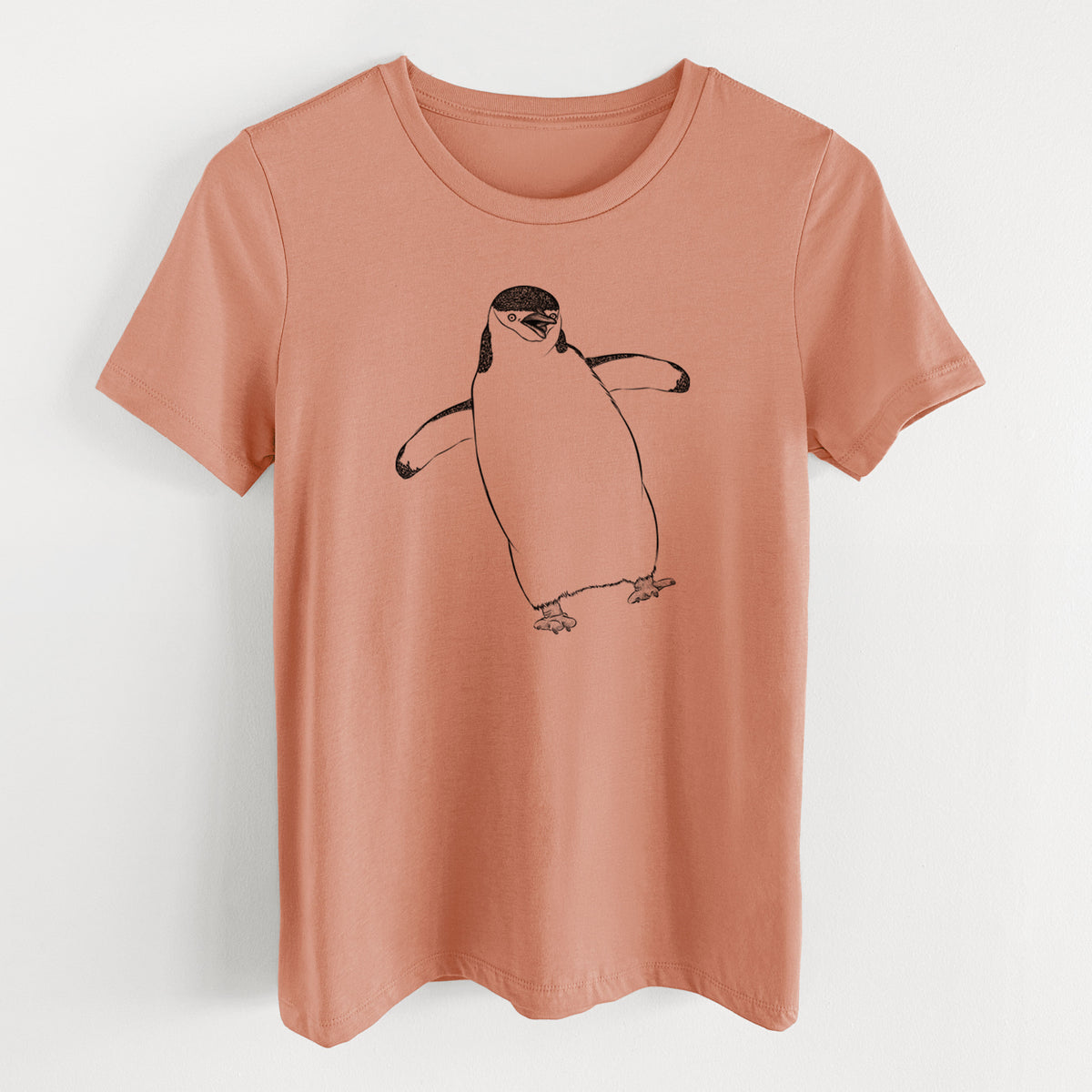 Terracotta orange women's relaxed fit cotton t-shirt laid flat, printed with a black ink illustration of a chinstrap penguin standing with its flippers out.