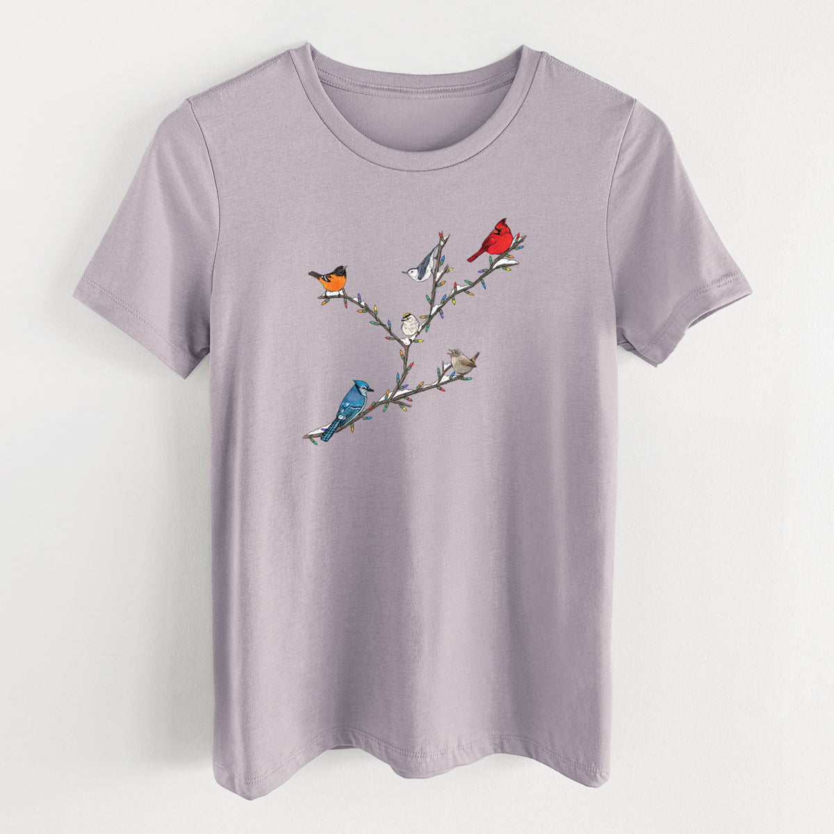 Light violet women's relaxed fit cotton t-shirt laid flat, printed with a full-color illustration of winter backyard birds, including a cardinal, blue jay and robin, perched on bare branches.