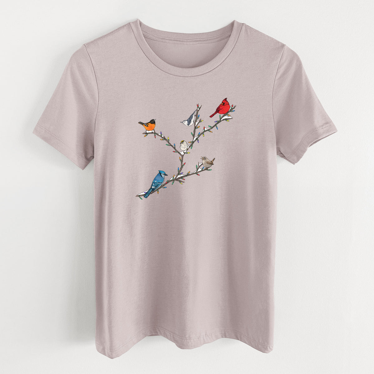 Pink gravel women's relaxed fit cotton t-shirt laid flat, printed with a full-color illustration of winter backyard birds, including a cardinal, blue jay and robin, perched on bare branches.