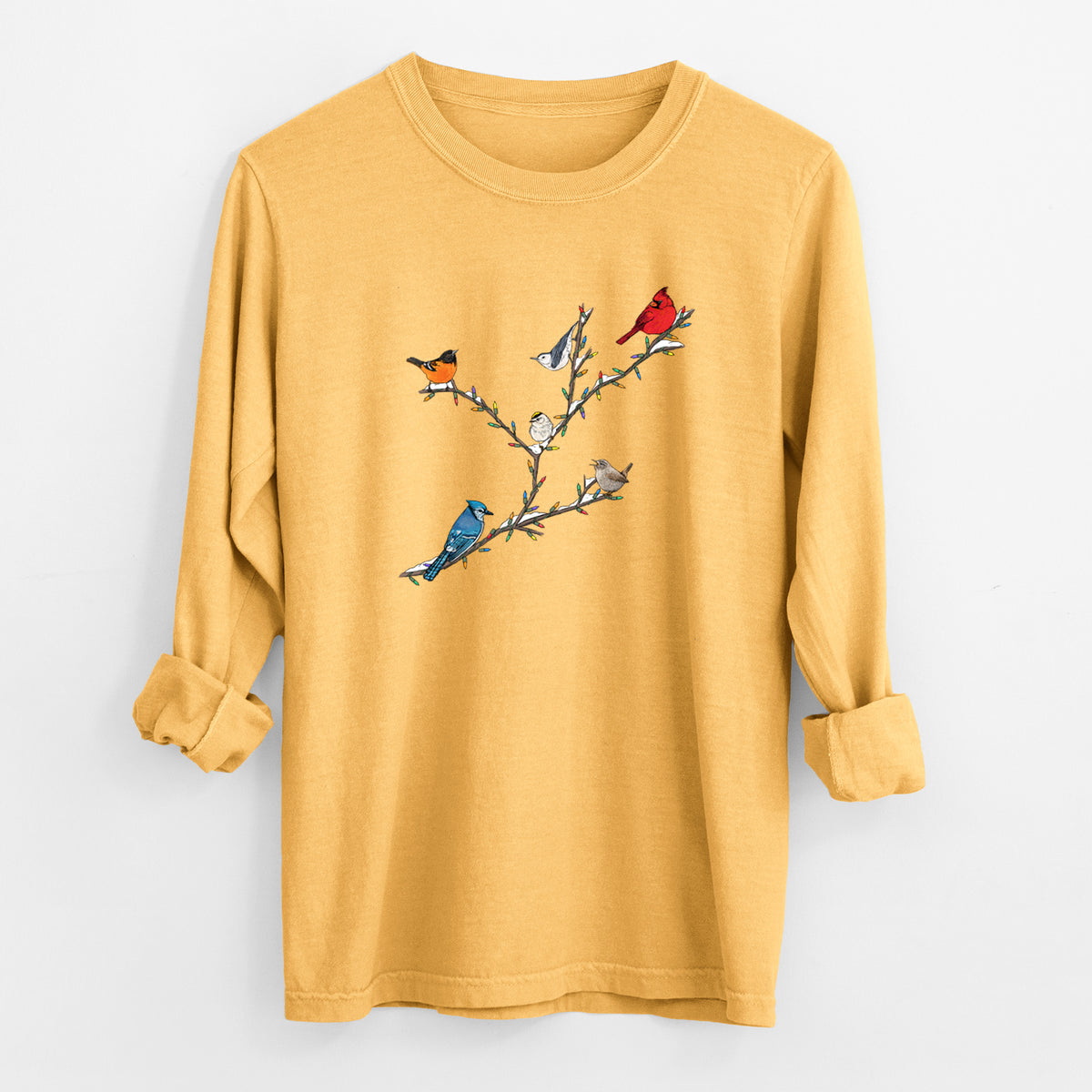Golden wheat yellow Comfort Colors long sleeve shirt laid flat with the cuffs rolled, printed with a full-color illustration of winter backyard birds, including a cardinal, blue jay and robin, perched on bare branches.