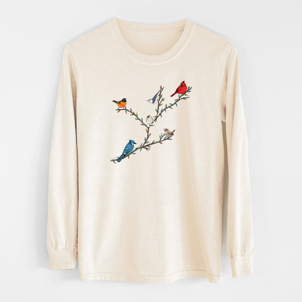 Ivory Comfort Colors long sleeve shirt laid flat, printed with a full-color illustration of winter backyard birds, including a cardinal, blue jay and robin, perched on bare branches.