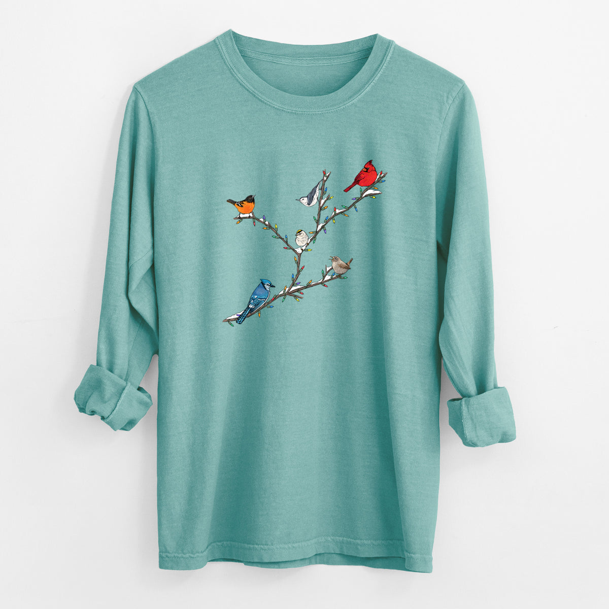 Reef green Comfort Colors long sleeve shirt laid flat with the cuffs rolled, printed with a full-color illustration of winter backyard birds, including a cardinal, blue jay and robin, perched on bare branches.