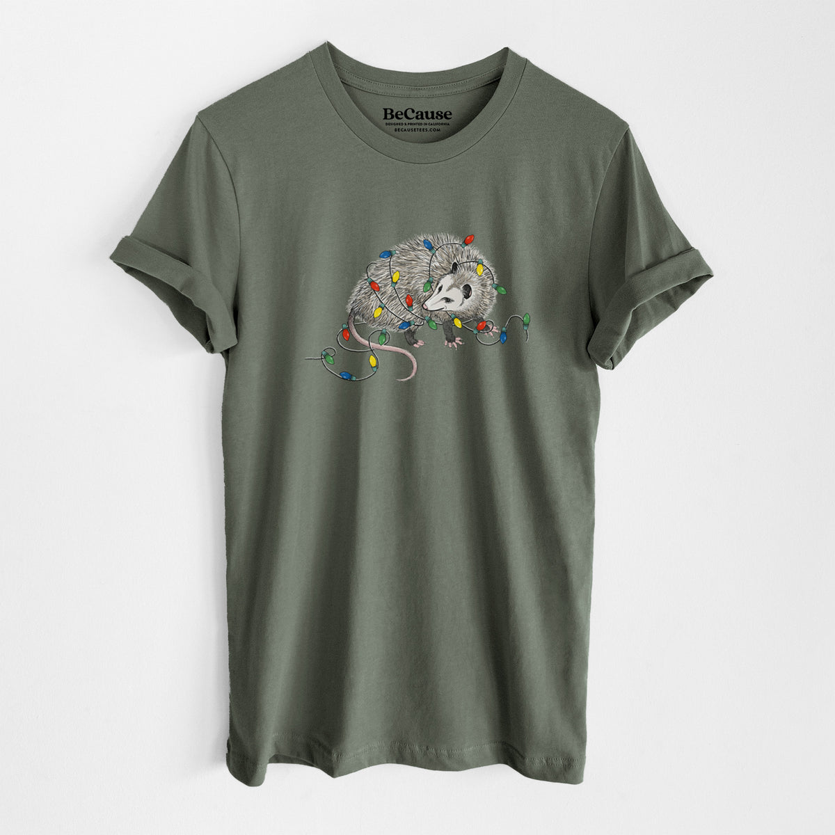 Military green lightweight cotton t-shirt laid flat, printed with a black ink opossum tangled in a string of colorful holiday lights.
