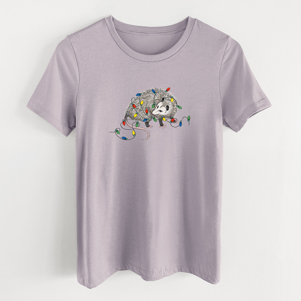 Light violet women's relaxed fit cotton t-shirt laid flat, printed with a black ink opossum tangled in a string of colorful holiday lights.