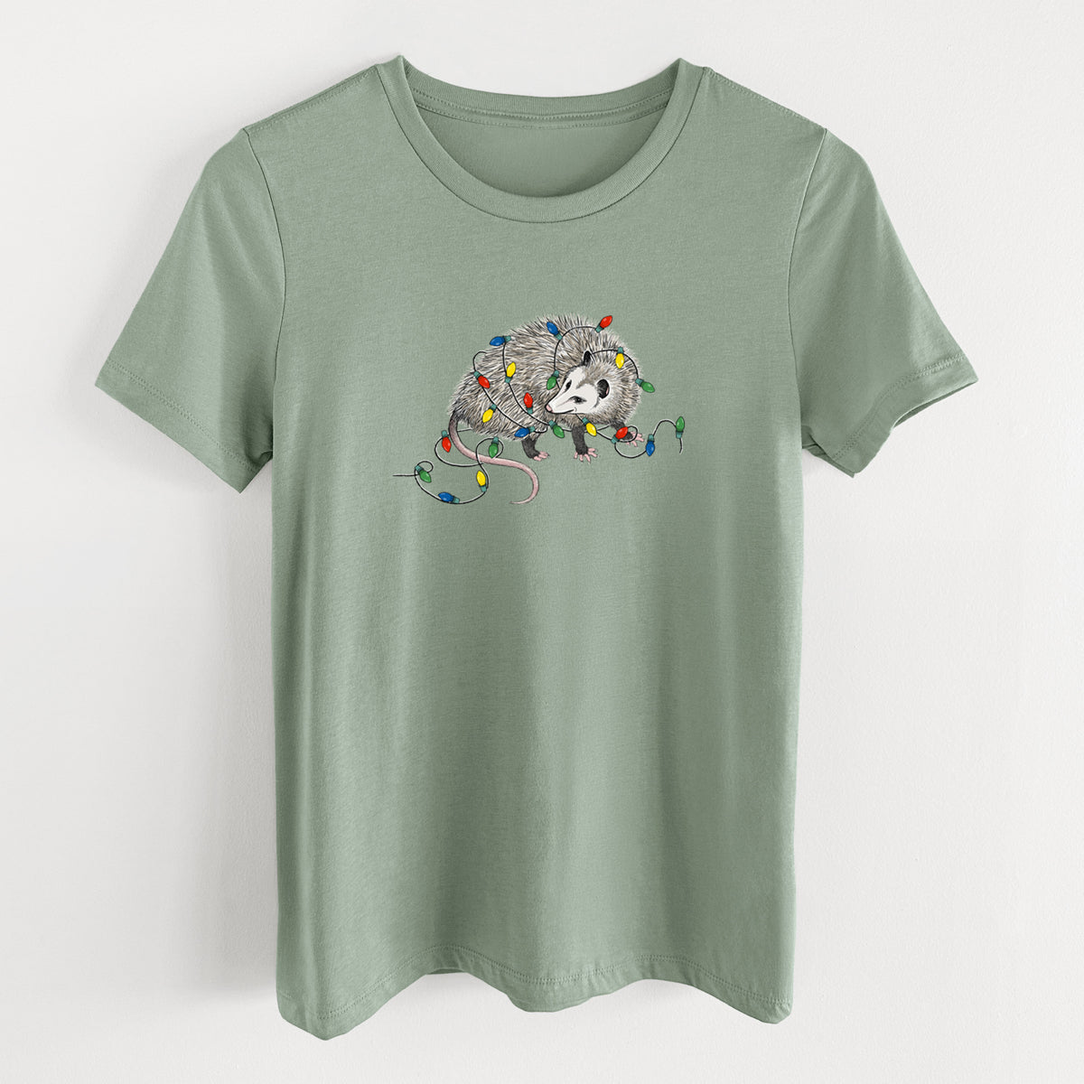 Sage green women's relaxed fit cotton t-shirt laid flat, printed with a black ink opossum tangled in a string of colorful holiday lights.