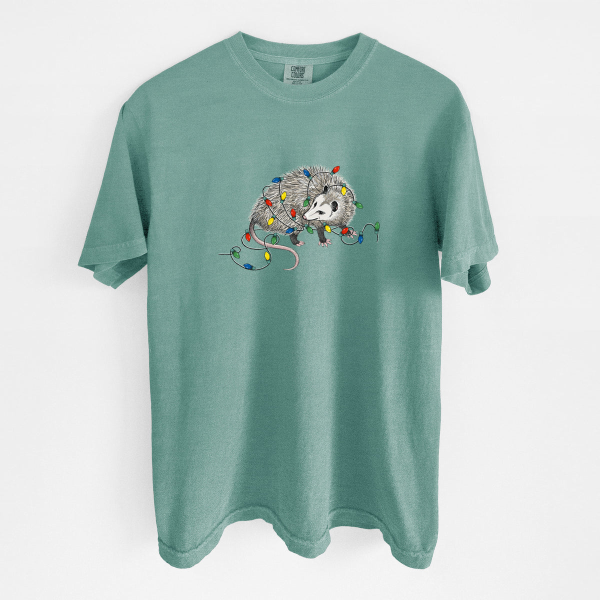 Reef green Comfort Colors t-shirt laid flat, printed with a black ink opossum tangled in a string of colorful holiday lights.