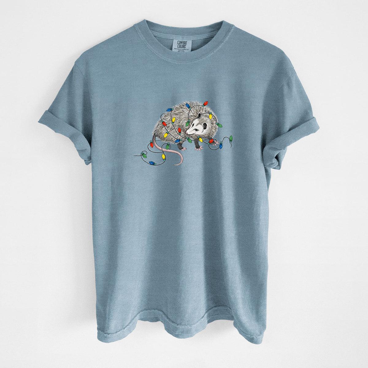 Steel blue Comfort Colors t-shirt laid flat, printed with a black ink opossum tangled in a string of colorful holiday lights.