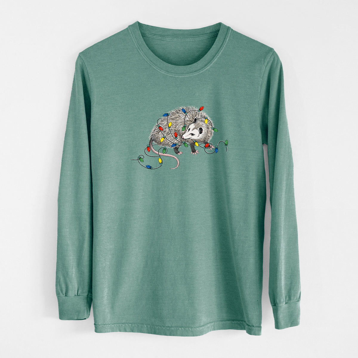 Pine green Comfort Colors long sleeve shirt laid flat, printed with a black ink opossum tangled in a string of colorful holiday lights.