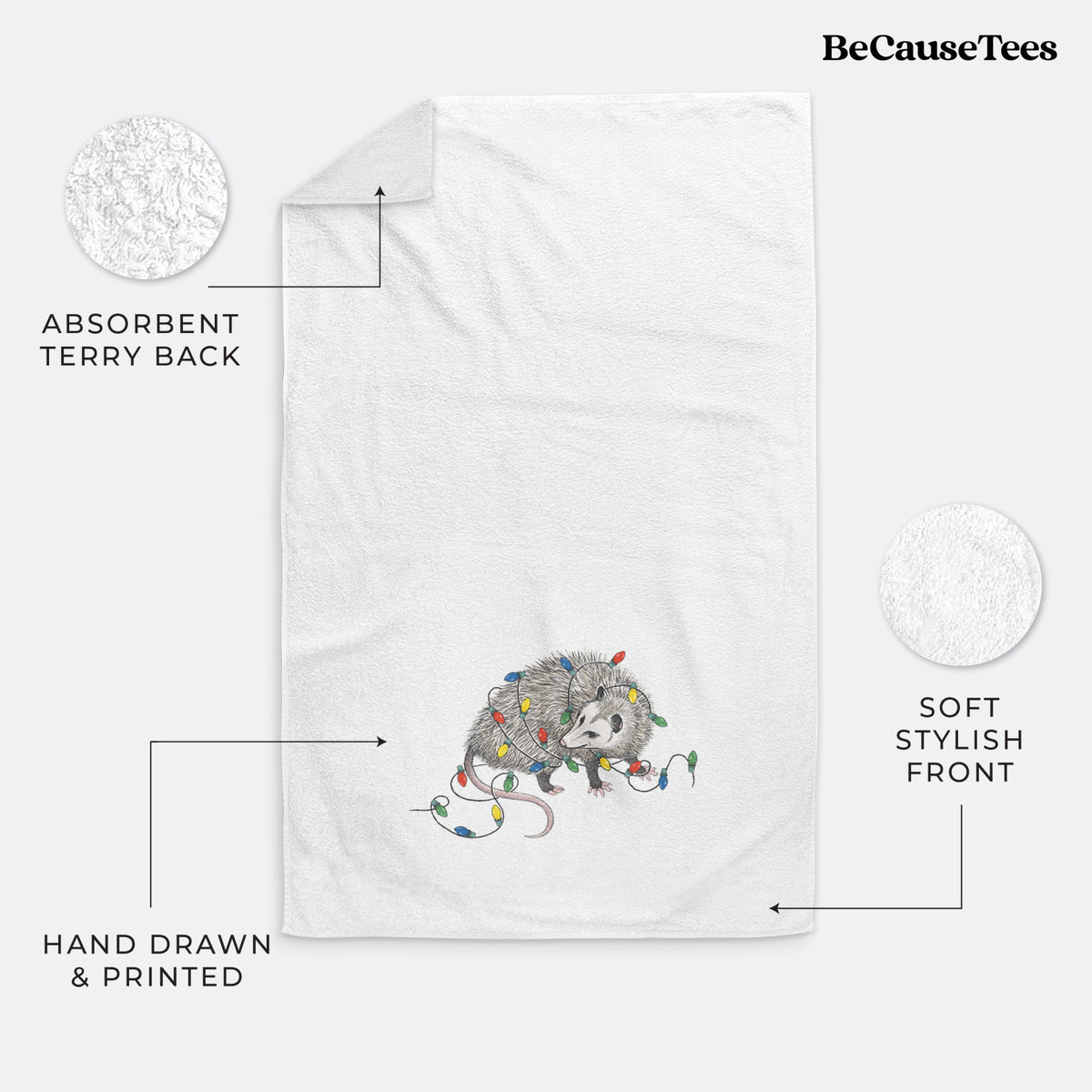 White hand towel printed with a black ink opossum tangled in a string of colorful holiday lights.