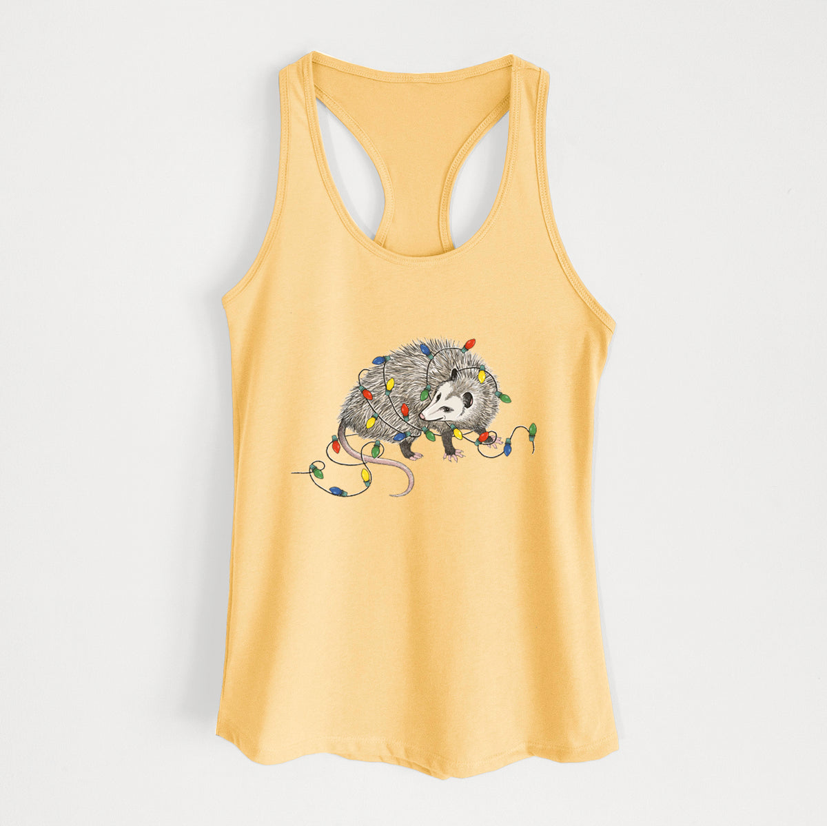 Banana cream women's racerback tank top laid flat, printed with a black ink opossum tangled in a string of colorful holiday lights.