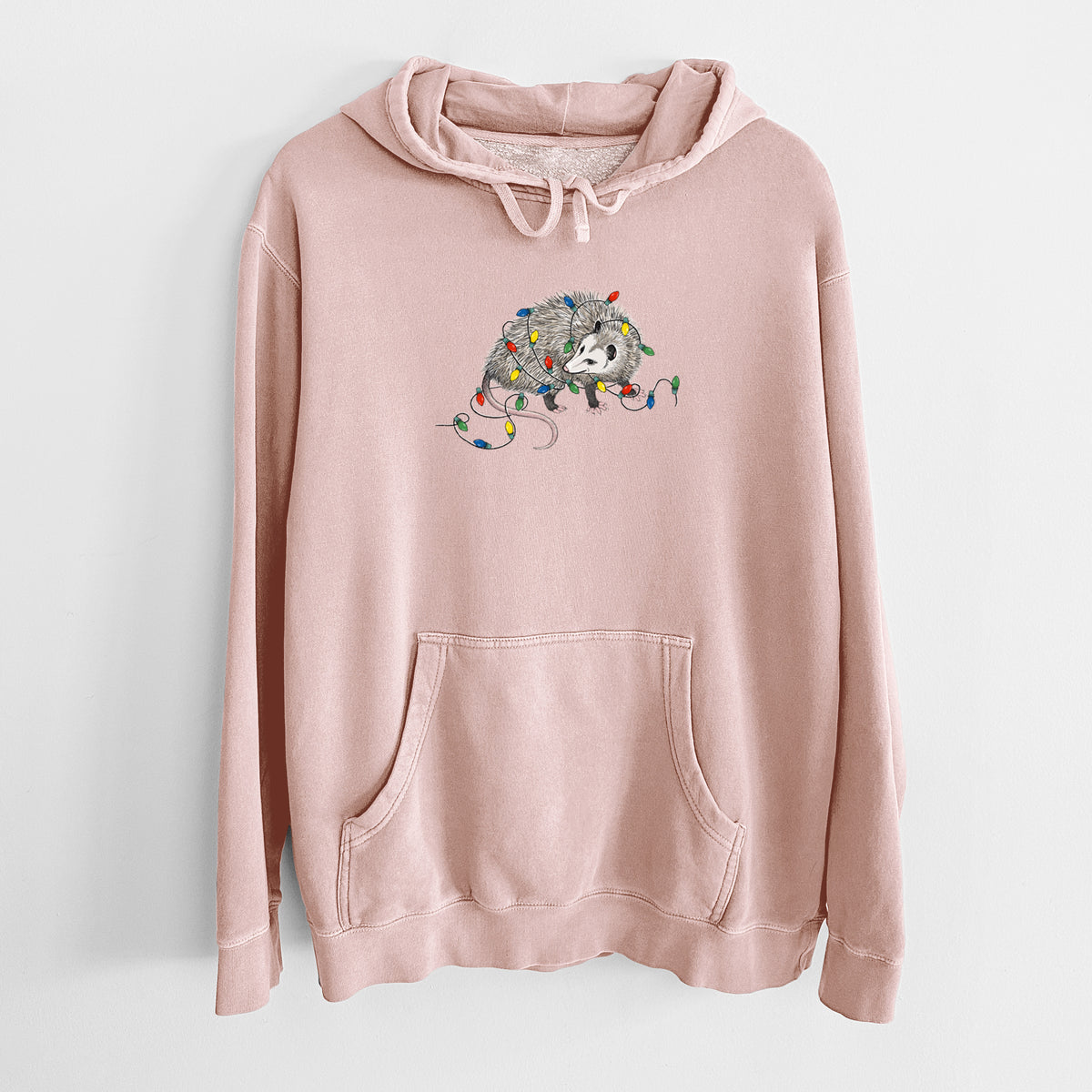Dusty pink pigment dyed hoodie laid flat, printed with a black ink opossum tangled in a string of colorful holiday lights.