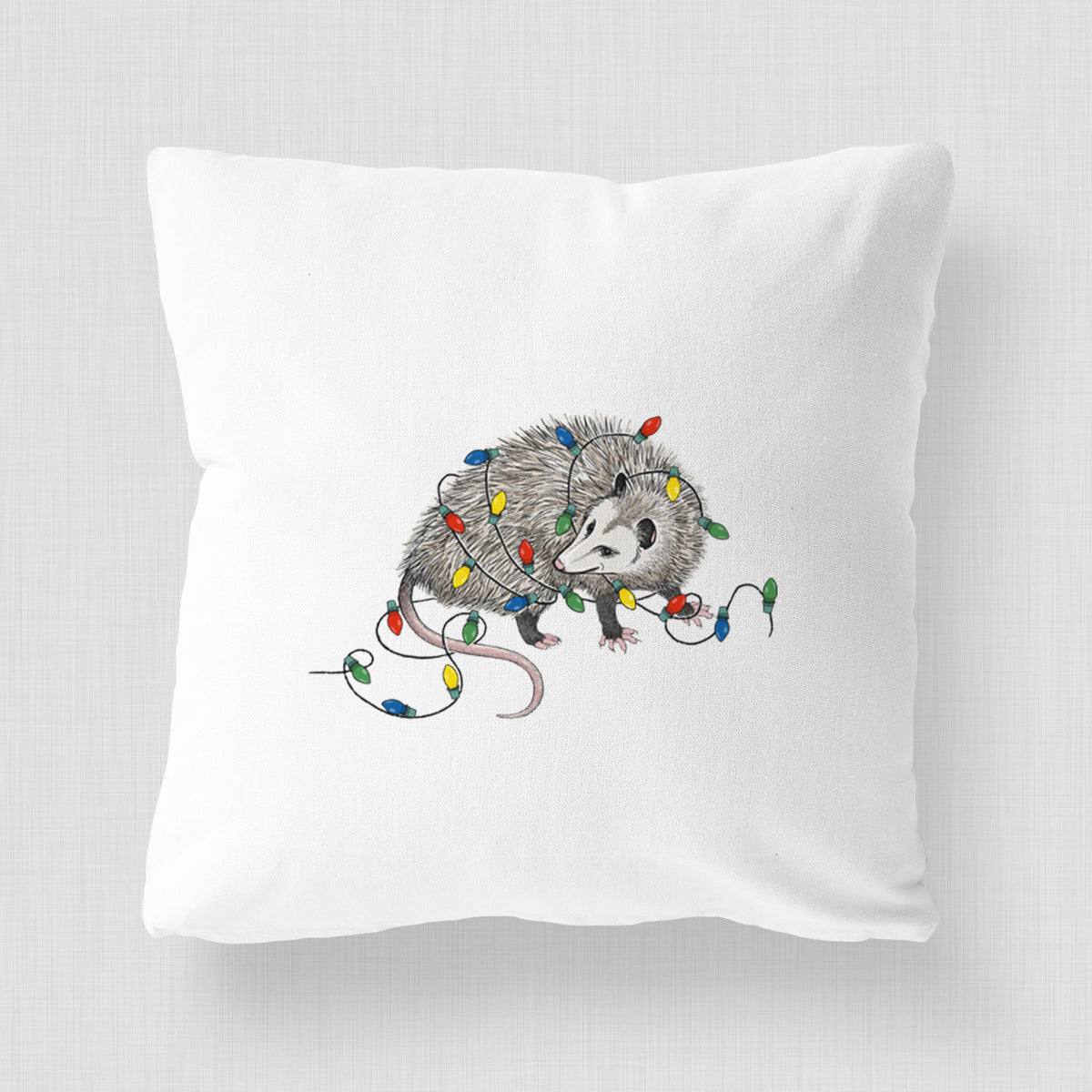 White pillow cover printed with a black ink opossum tangled in a string of colorful holiday lights.